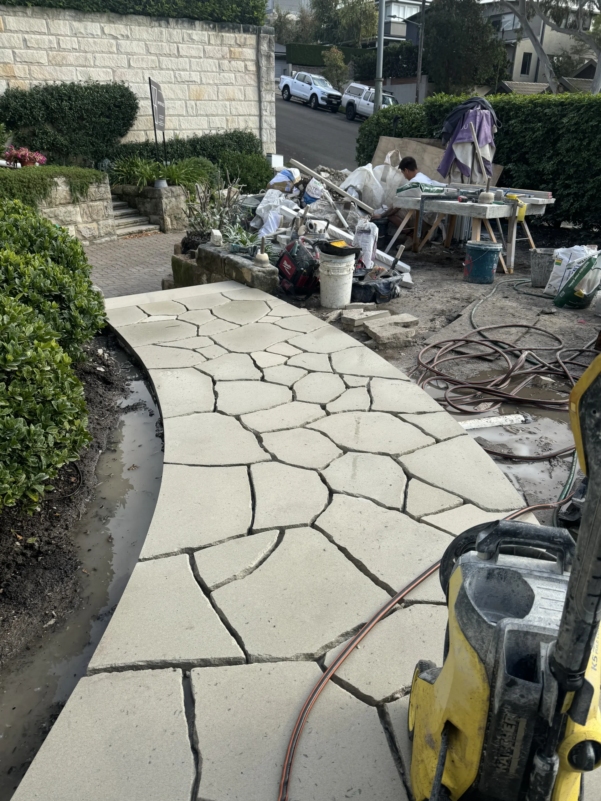 Sandstone crazy paving being laid on a garden path