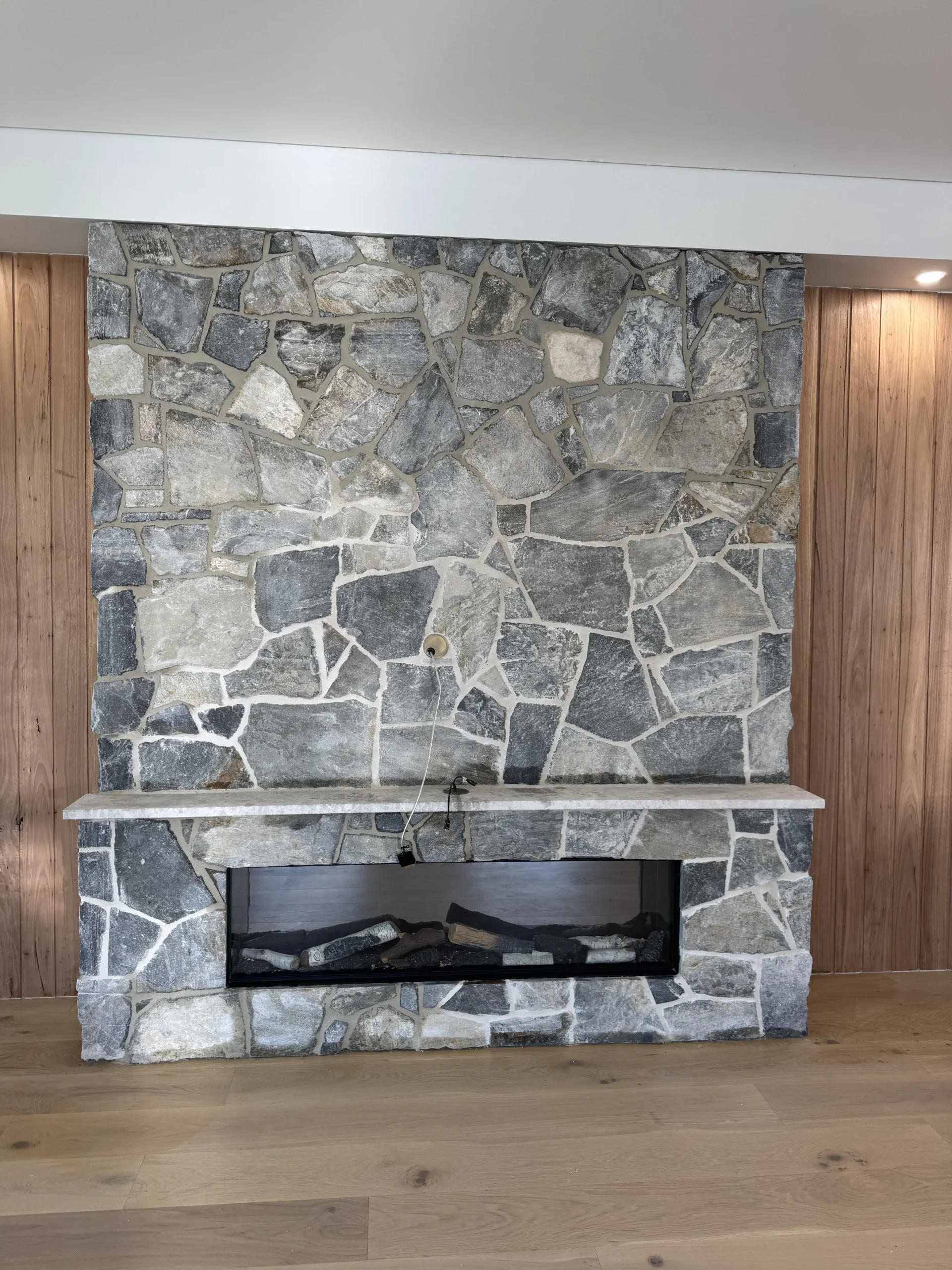 Crazy stone cladding on an indoor fireplace feature wall