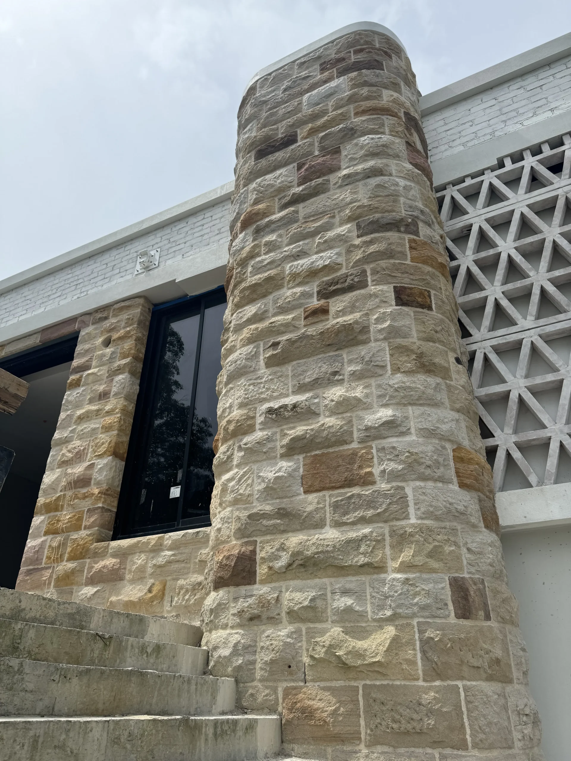 Round sandstone-clad column beside a set of stone steps
