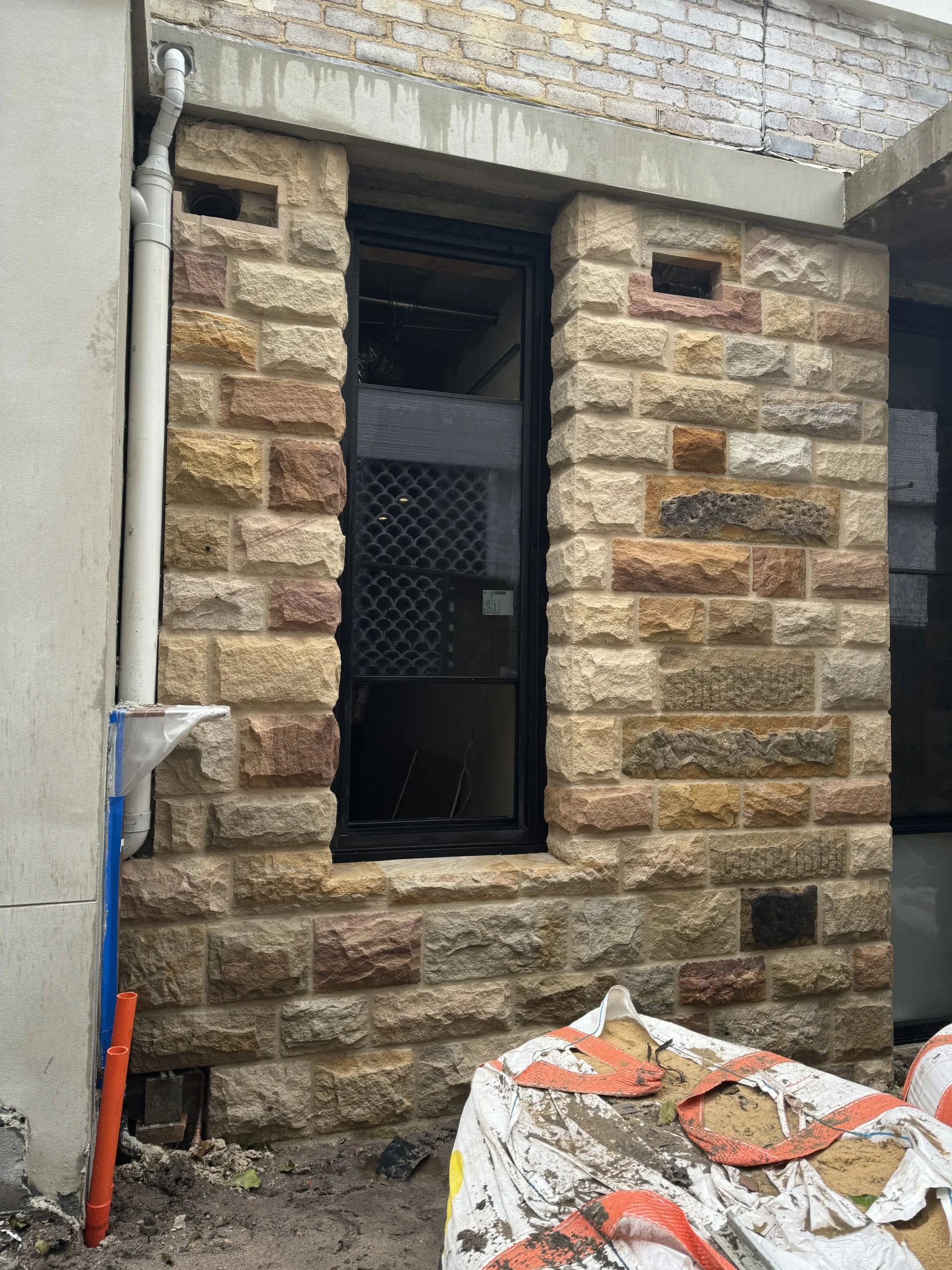Sandstone-clad chimney against a rendered weatherboard home