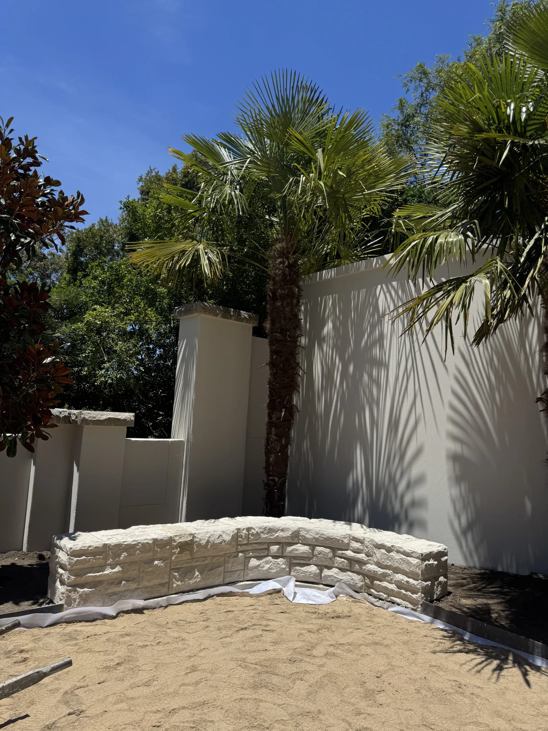 Sandstone garden wall in a courtyard lined with palms