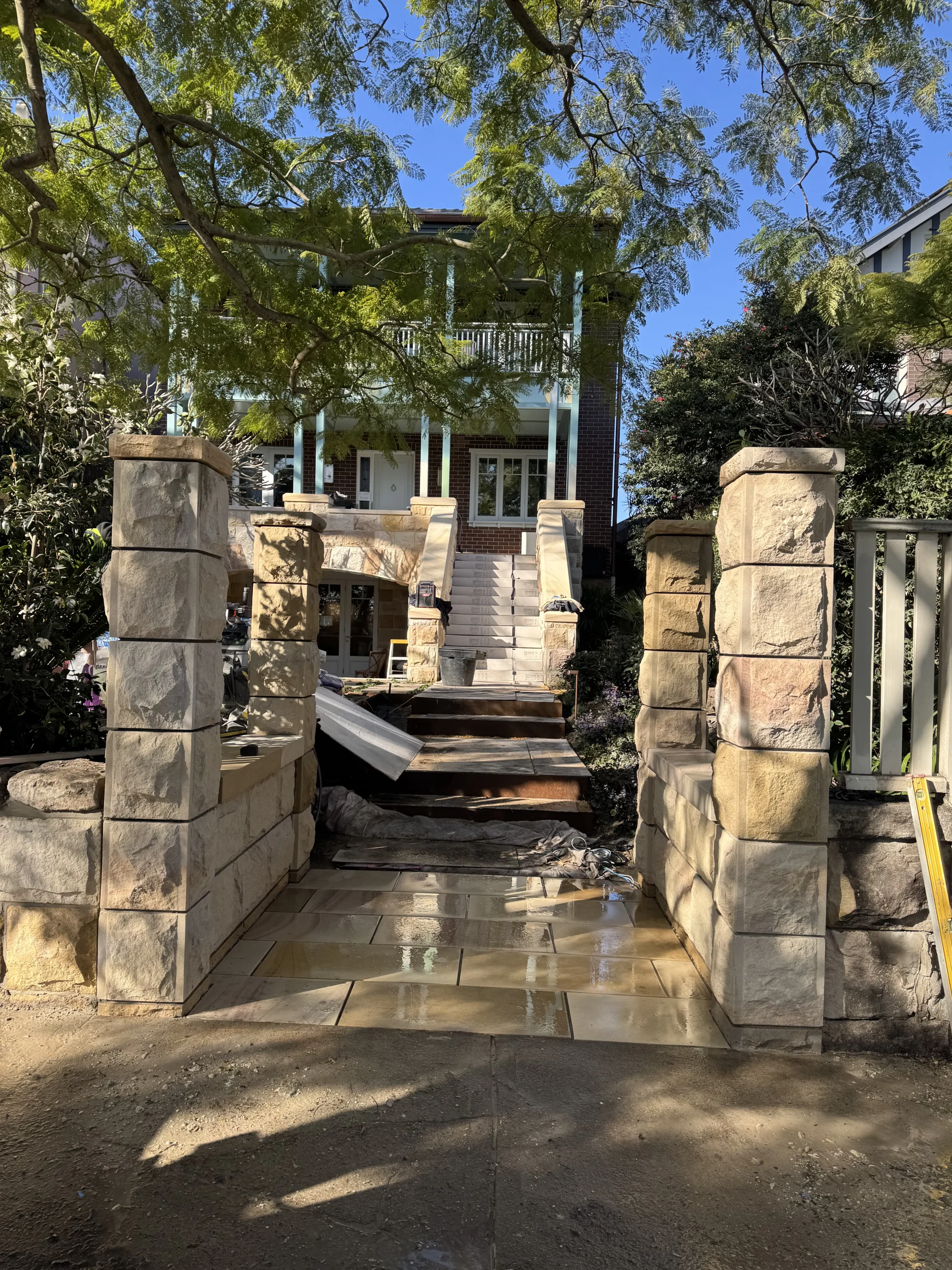 Stonemason installing sandstone-clad pergola pillars