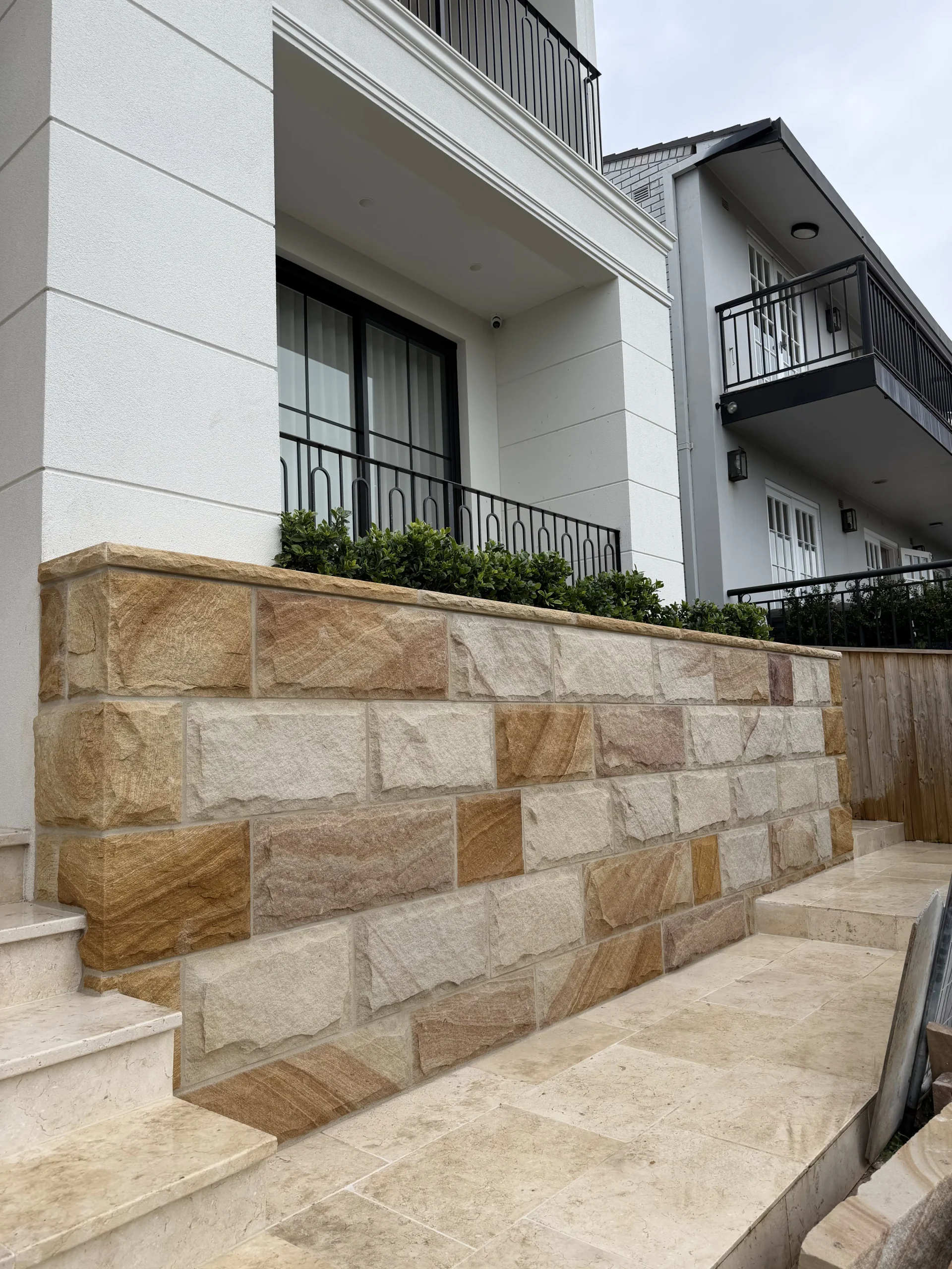 Sandstone-clad pier against a modern home facade