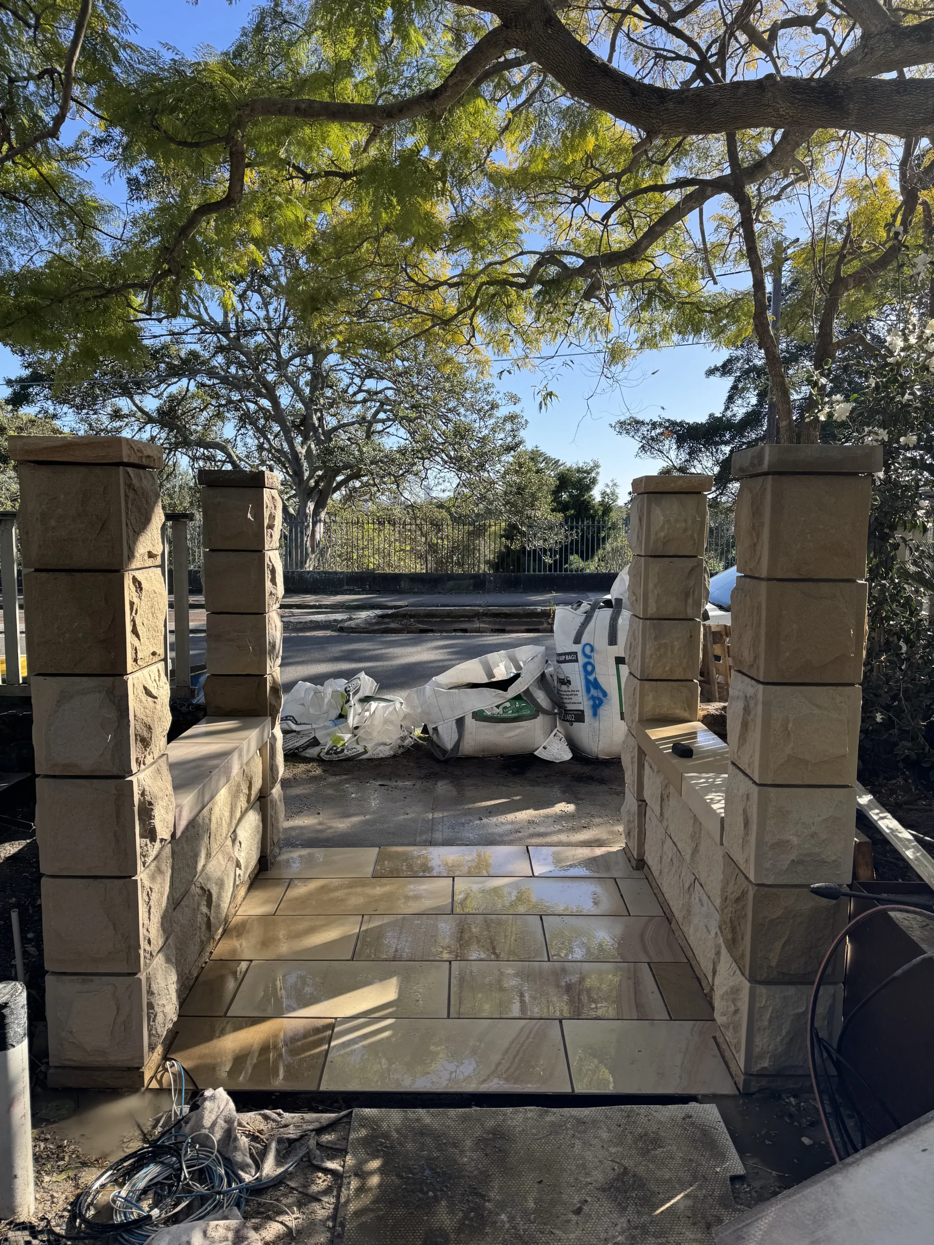 Sandstone steps and wall being built beneath a pergola