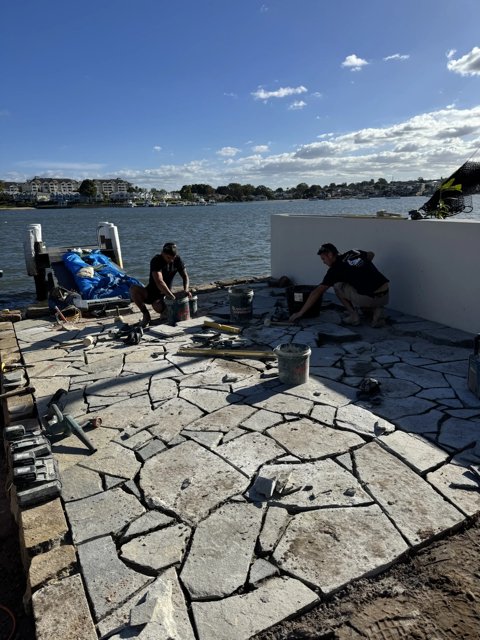 Prism Stonemasonry team laying crazy paving on a waterfront terrace